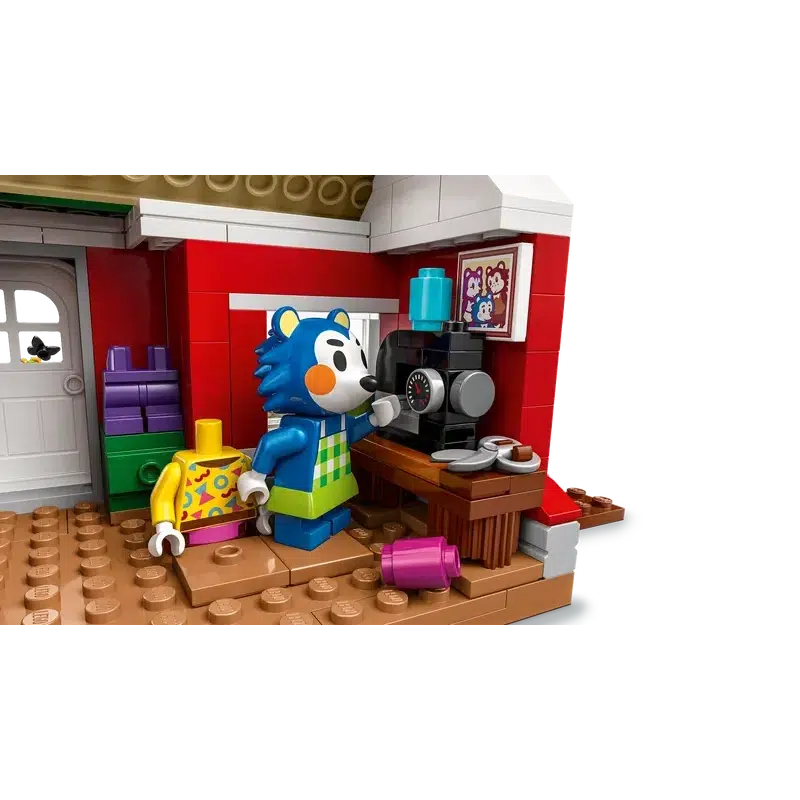 a close up of the inside of the building with one of the figures standing by a lego sewing machine with a colorful shirt behind the minifig.