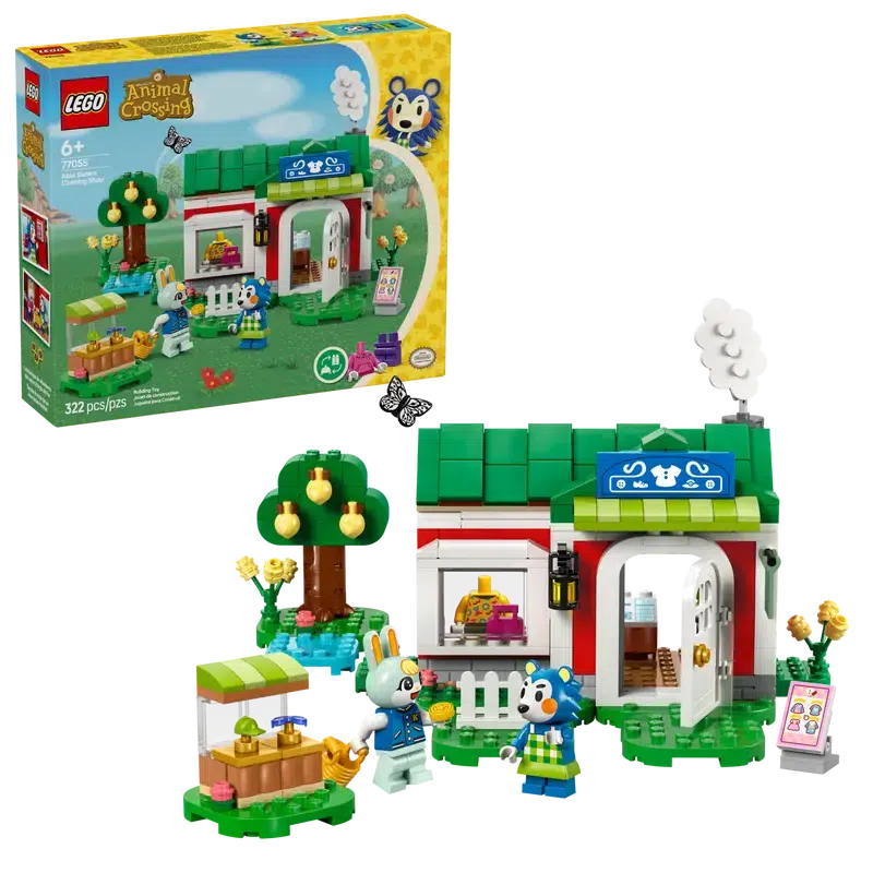 The lego set shown in front of it's box. There is a lego shop front, two figures, and a tree and shop stall.