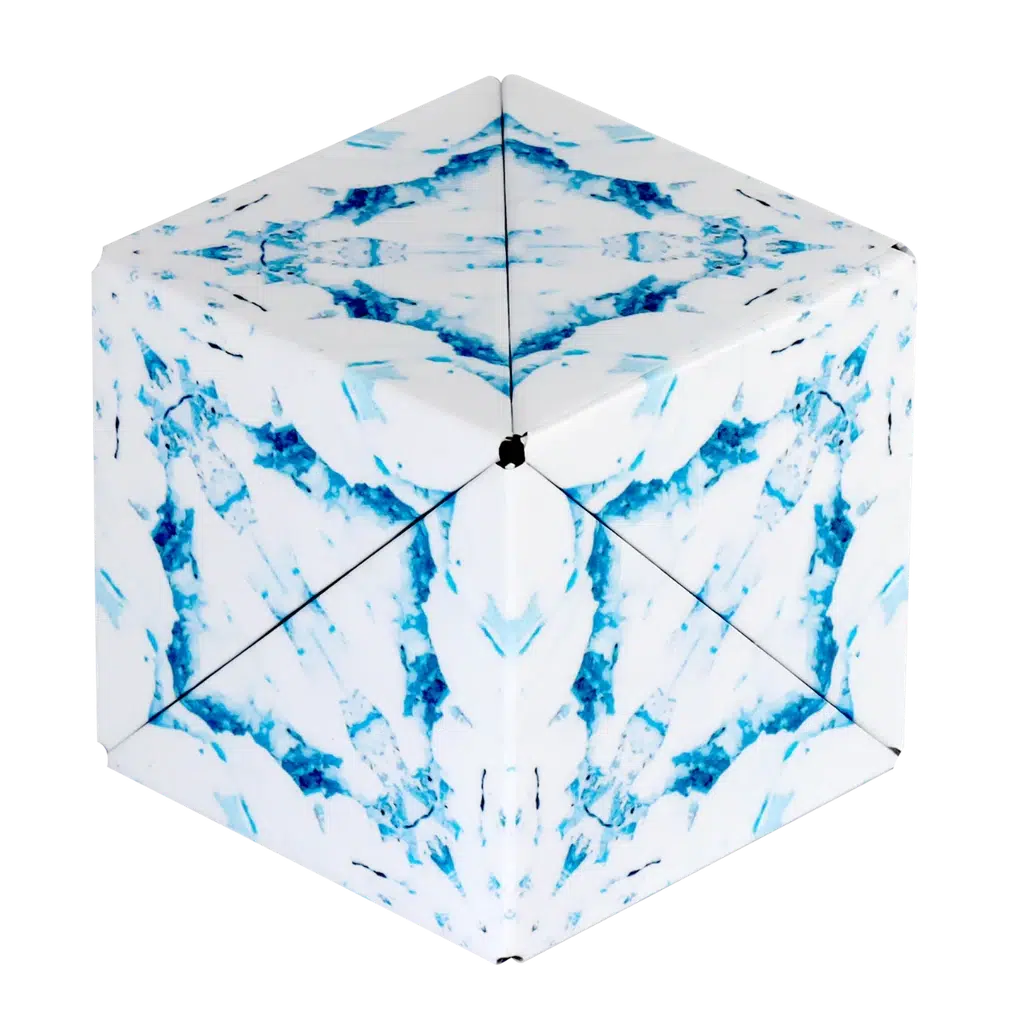 A geometric paper sculpture with a cube-like shape, reminiscent of a Shashibo, featuring blue and white abstract patterns that evoke magnetic puzzle cubes.