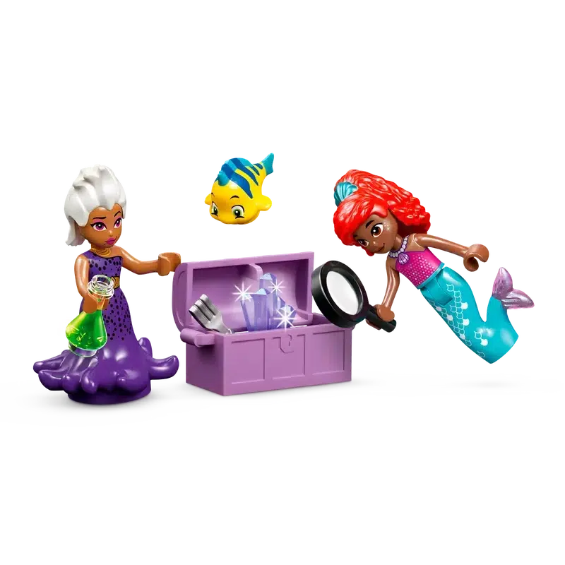 Two mermaid-themed LEGO figures: one with a purple tail holding a potion, another with a red tail inspecting a treasure chest with a magnifying glass, accompanied by a small yellow fish figure. This enchanting set is the perfect building toy for all underwater adventure seekers.