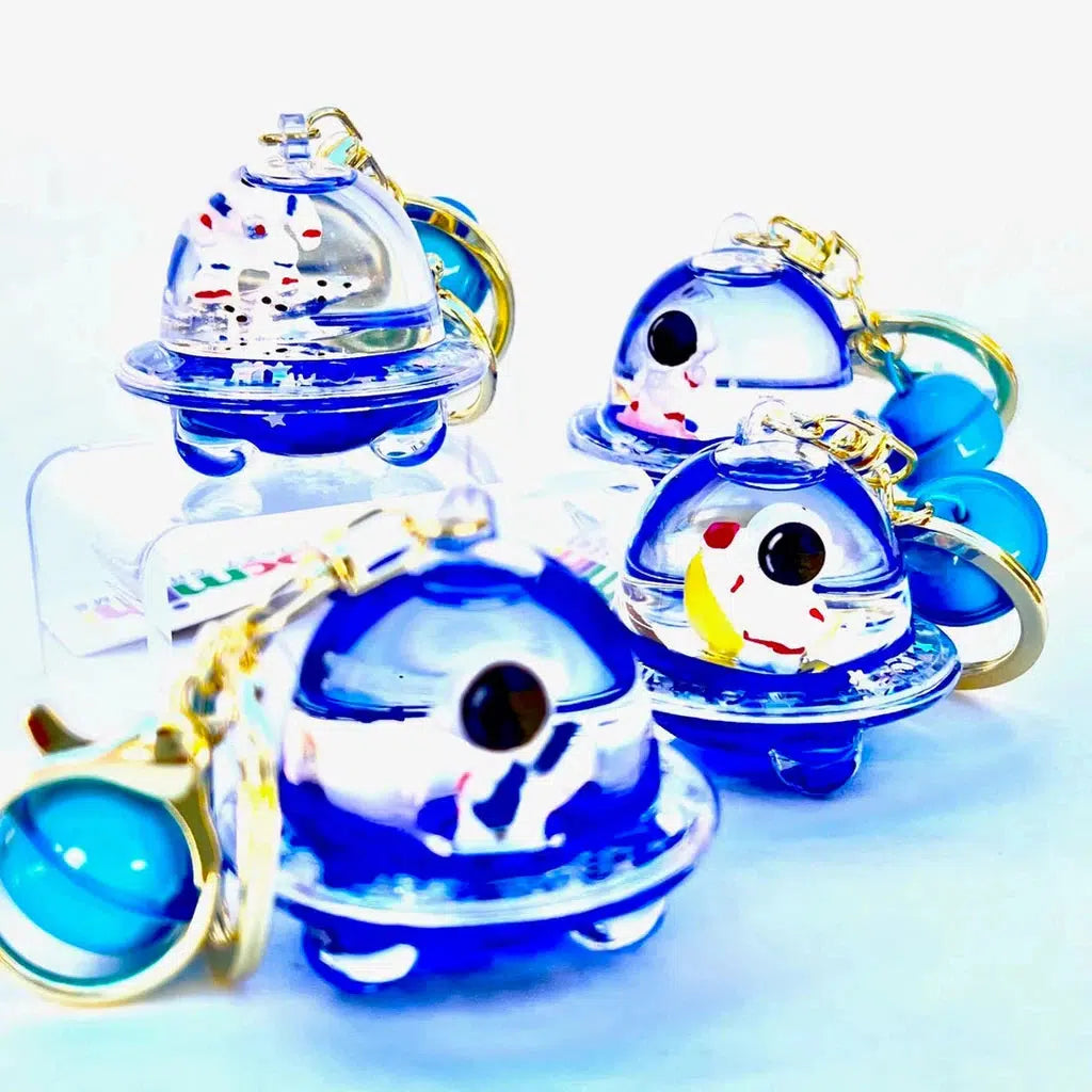 Four blue and clear keychain charms resembling UFOs with small figures inside, each featuring a quirky twist as silly animal charms, all placed against a white background. Perfect for adding some fun to your key ring clip!