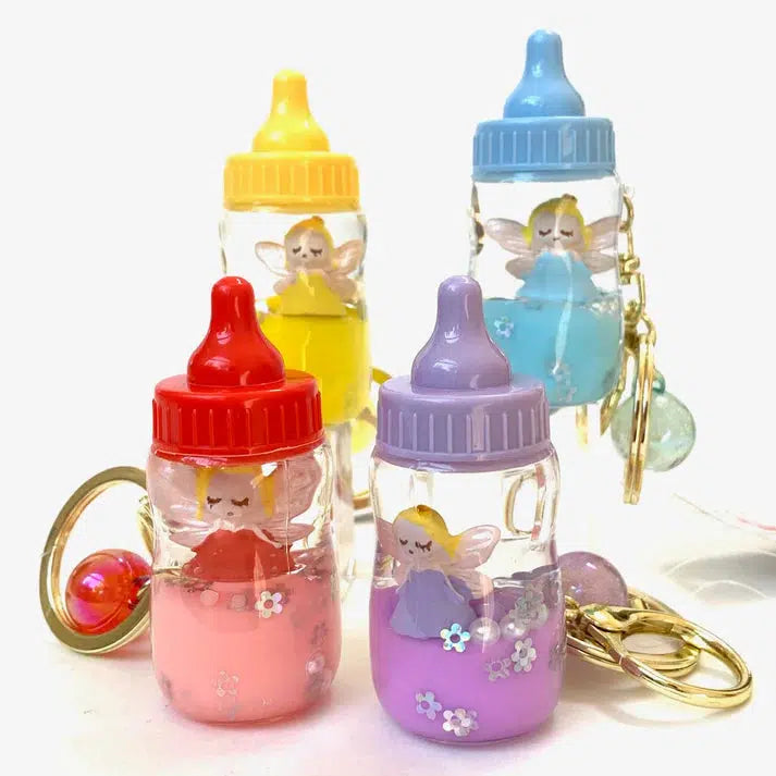 Four colorful keychains shaped like baby bottles with small fairy figurines inside, each showcasing a unique hue—yellow, red, purple, and blue. These assorted designs add a whimsical touch to any collection. The perfect key charm for those who love playful accessories!