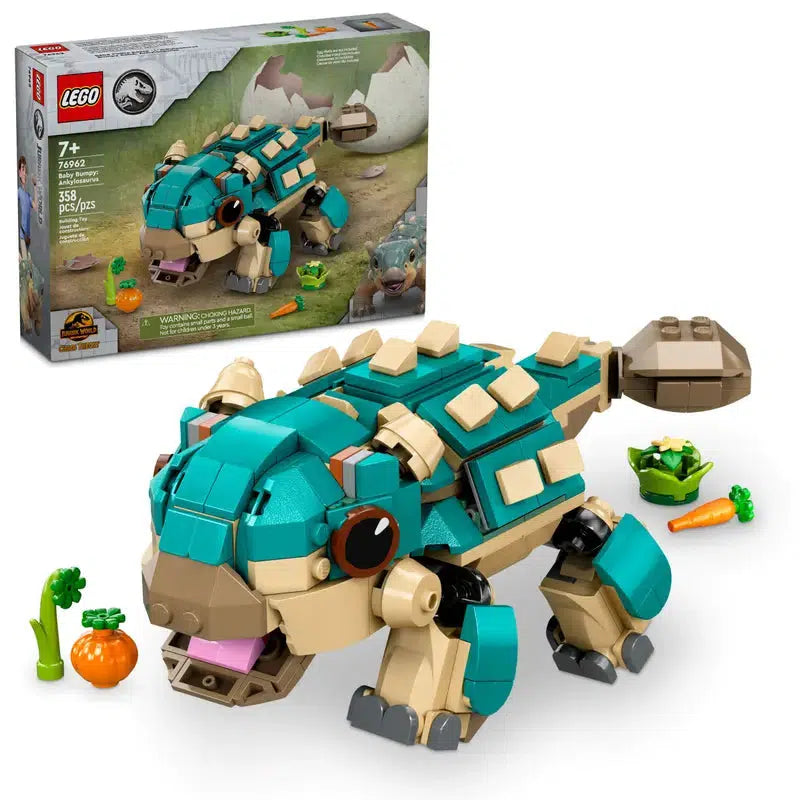 A LEGO masterpiece featuring a blue and beige dinosaur-like creature inspired by Jurassic World, built with vibrant blocks. The box is in the background, surrounded by small vegetable pieces, adding an adventurous touch to this prehistoric scene.