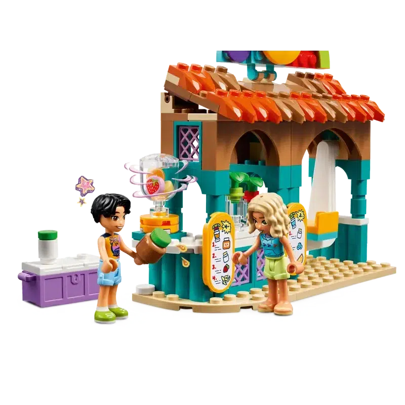 Two LEGO figures enjoy a colorful role-play toy juice stand. One holds a drink, while a blender with fruit is nearby. The bright and playful setup features detailed decorations, making it a perfect addition to kids' food playsets.