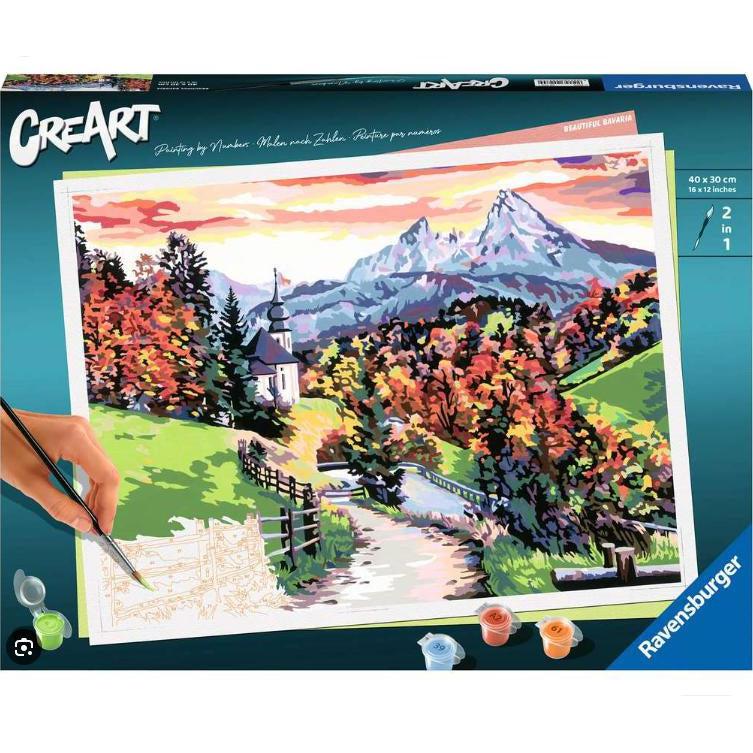 the beautiful bavaria paint by numbers box shows a 2 in 1 paint brush painting a stunning landscape with a winding dirt road fenced in. autumn orage is on the trees with a building in the background framed in two stunning mountains basking in the sunset.