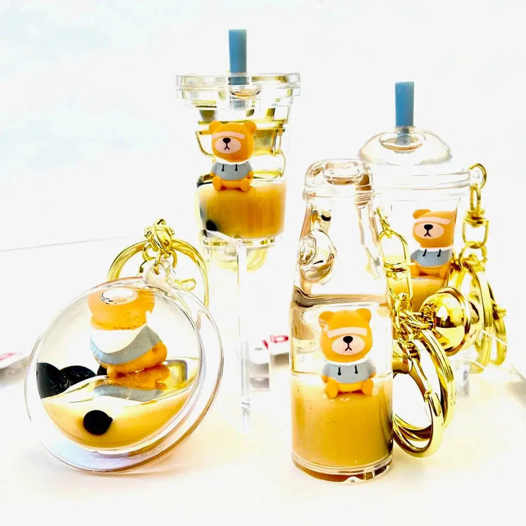 Clear containers with bear floaty charms inside, resembling bubble tea drinks. These whimsical keyrings are adorned with gold chains and silly animal charms.