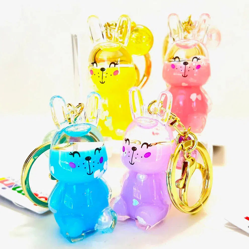 A collection of colorful, transparent bunny floaty key charms in yellow, pink, blue, and purple features assorted designs of silly animals and is displayed on a white background.