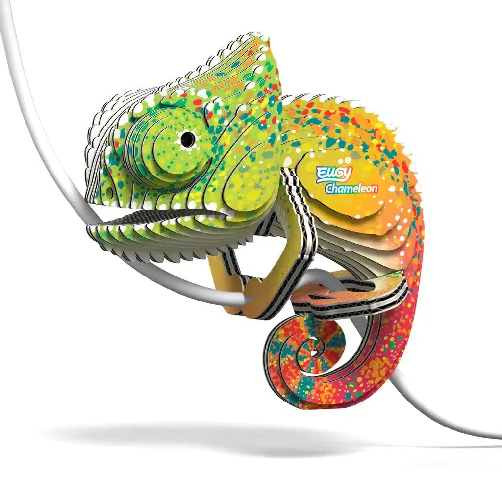 A colorful, abstract chameleon sculpture crafted as a 3D puzzle with layered sections and a "Bucky Chameleon" logo, perched on a white arc. Created by EUGY, it showcases an eco-friendly design.