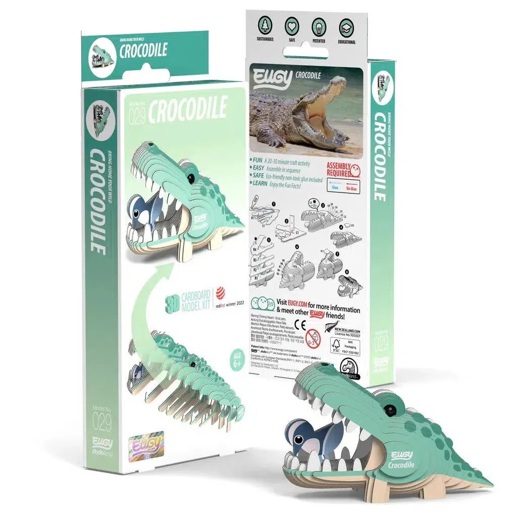 Eco-friendly crocodile-themed cardboard model kit, shown assembled and in packaging. This 3D puzzle includes graphics and instructions for building a cartoon crocodile figure, subtly introducing STEM concepts through engaging assembly.