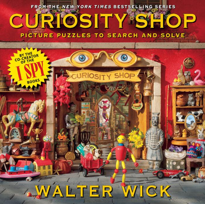 An I Spy Book called Curiosity Shop. Picture puzzles to search and solve feature a wide array of items arranged to look like a tiny shop with a tiny man made of beads in front.