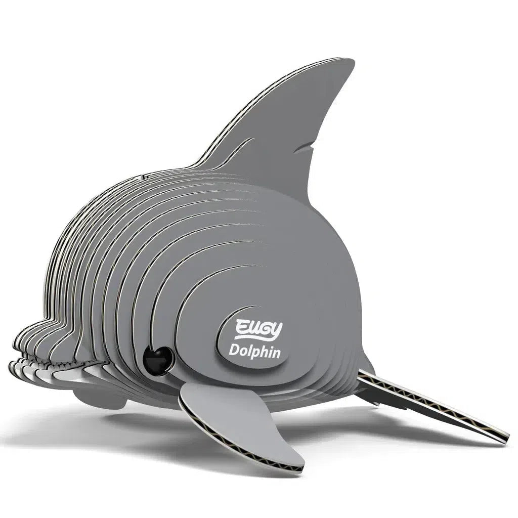 The EUGY eco-friendly 3D puzzle features a layered cardboard dolphin model with gray segments, a prominent dorsal fin, and a label on its side that reads "Dolphin.