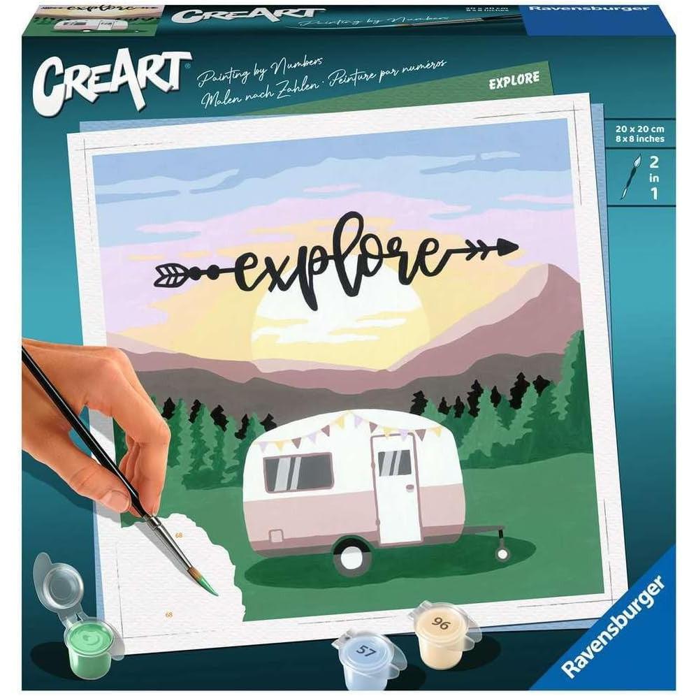 A Ravensburger painting kit box displays a paint-by-number scene featuring a camper, majestic mountains, and an "explore" caption. A hand skillfully uses the brush to color the unpainted canvas, making it perfect for arts and crafts enthusiasts.