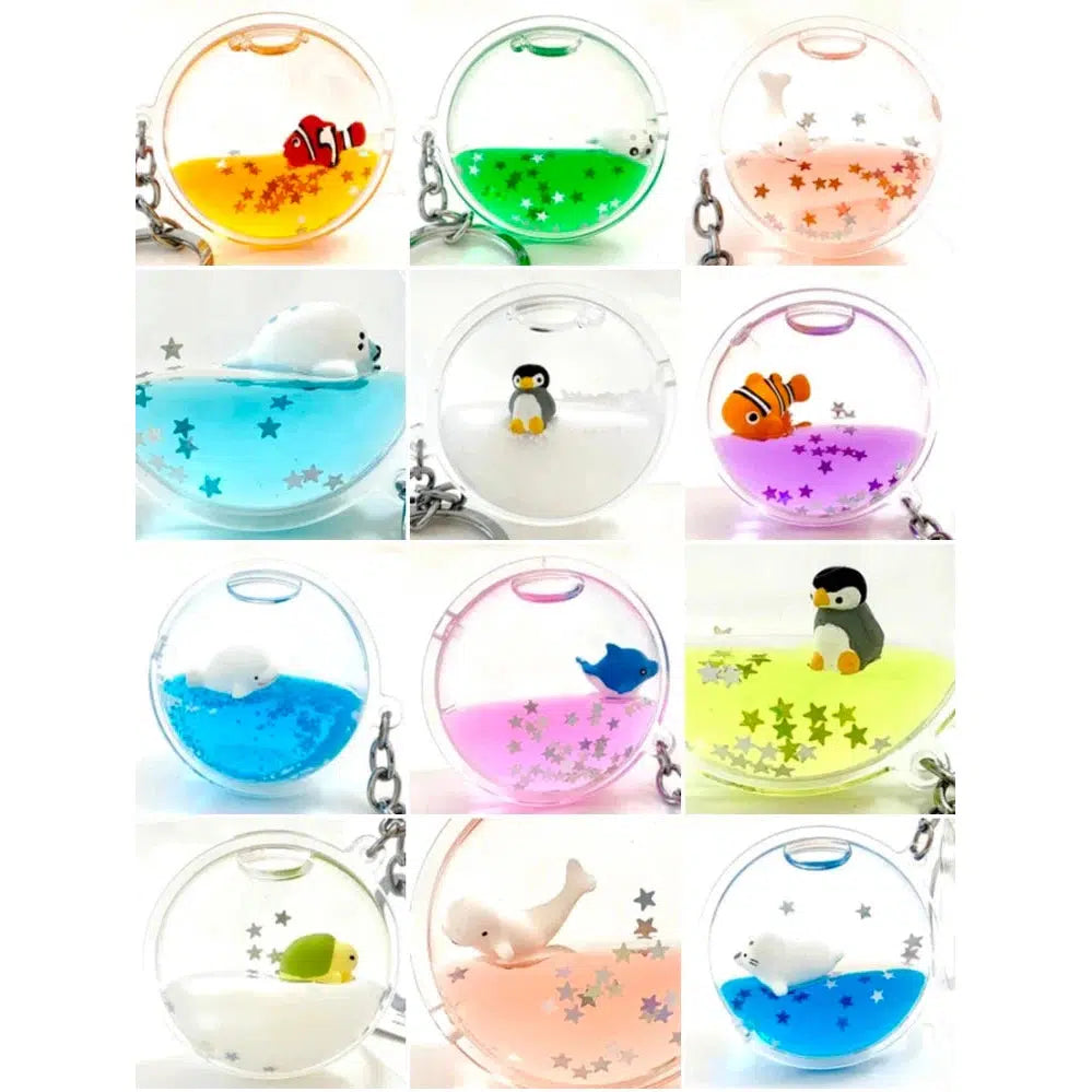 Twelve circular key rings filled with colored liquid, each featuring a floating sea charm with small toy sea animals and silver stars.