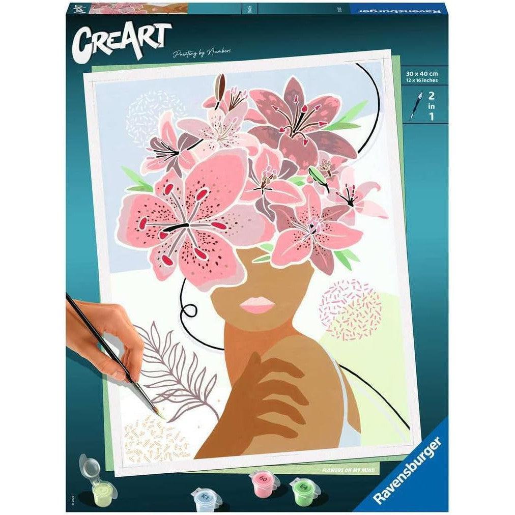 Ravensburger Paint by Numbers kit presents "Flowers on My Mind," a delightful arts and crafts kit with pink florals and a striking silhouette. Perfect for creative relaxation.