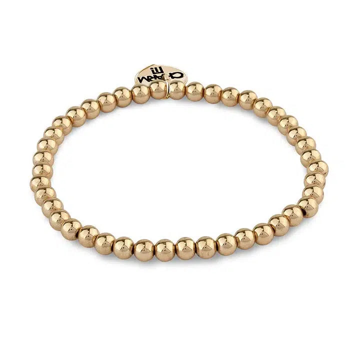 A gold beaded stretch bracelet with a small heart-shaped charm featuring engraved text makes the perfect arm candy.