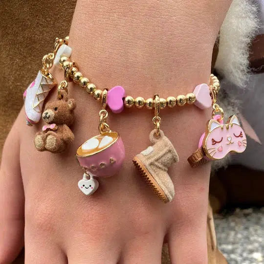 a wrist wearing a pink and gold charm bracelet