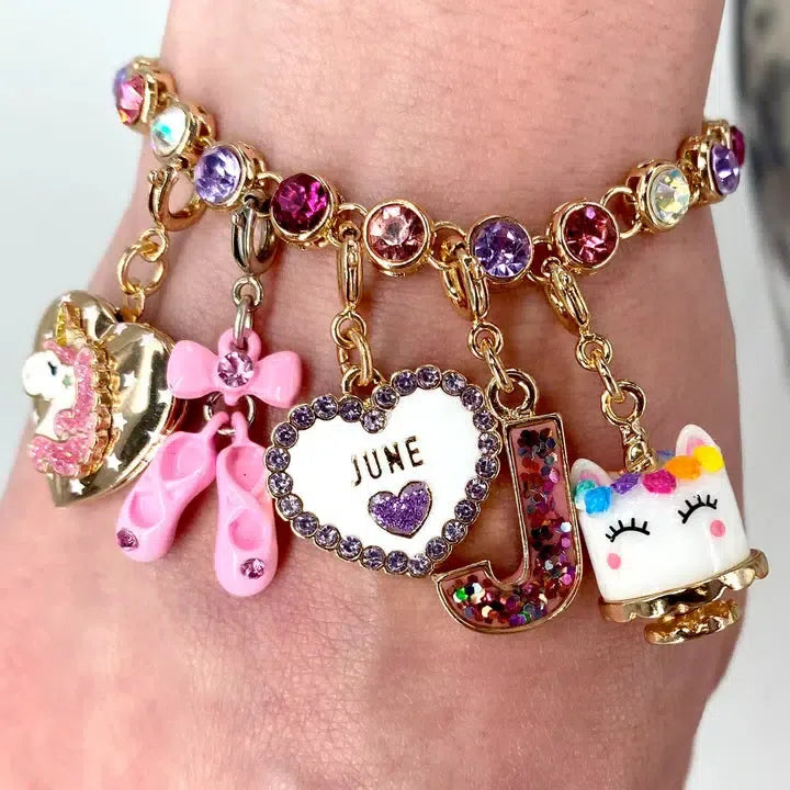 A charm bracelet adorned with delightful accents: a unicorn, pink ballet shoes, a heart inscribed with "June," the letter J, and a unicorn head. This customizable treasure sparkles with colorful gemstones and even includes an adorable dessert charm.