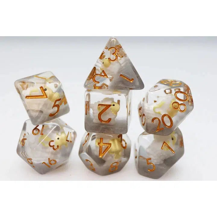 A set of translucent polyhedral dice, perfect for Dungeons and Dragons enthusiasts, features bronze numbers and tiny embedded dinosaur figures stacked in a pyramid shape.