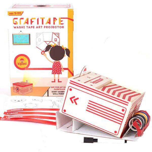 A do-it-yourself projector for kids, called GrafiTape, is displayed with a box, tape rolls, and projector components. The box indicates it's suitable for ages 5-99 and includes fun washi tape art projects. This craft kit ensures endless creative possibilities for all ages.