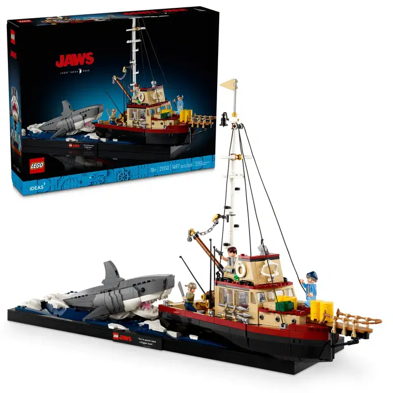 This collectible LEGO model features the iconic Orca boat from the Jaws movie, complete with three figures aboard and a massive shark emerging from the water on a flat display base.