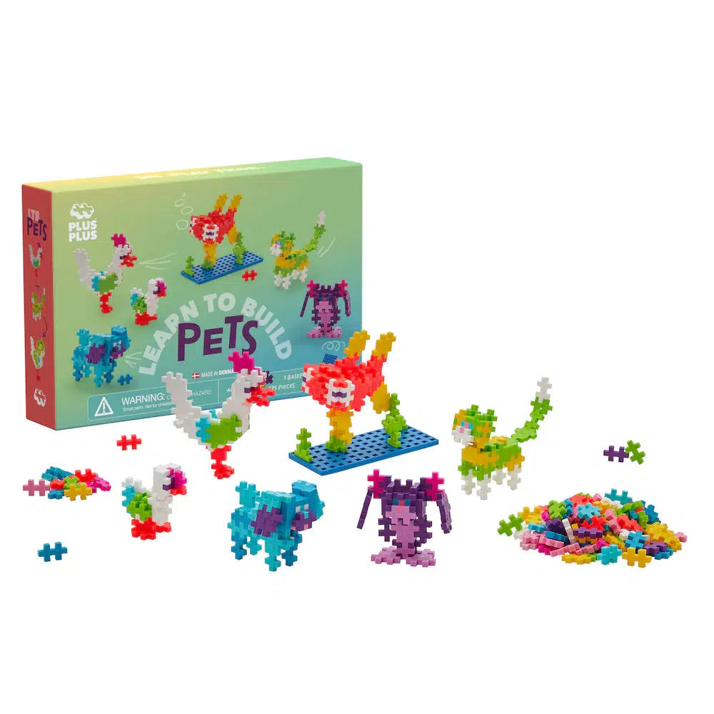 Box and plastic building pieces are artfully arranged as Plus-Plus Pets, depicting various animals. With scattered pieces on a white background, the scene invites creativity and endless possibilities.