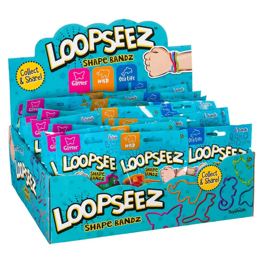 Display box of Loopseez Shape Bandz, featuring wearable shape wrist bands in collections like Glitter, Wild, and Sea Life. The packaging showcases colorful collectible bands with a "Collect &amp; Share!" message.