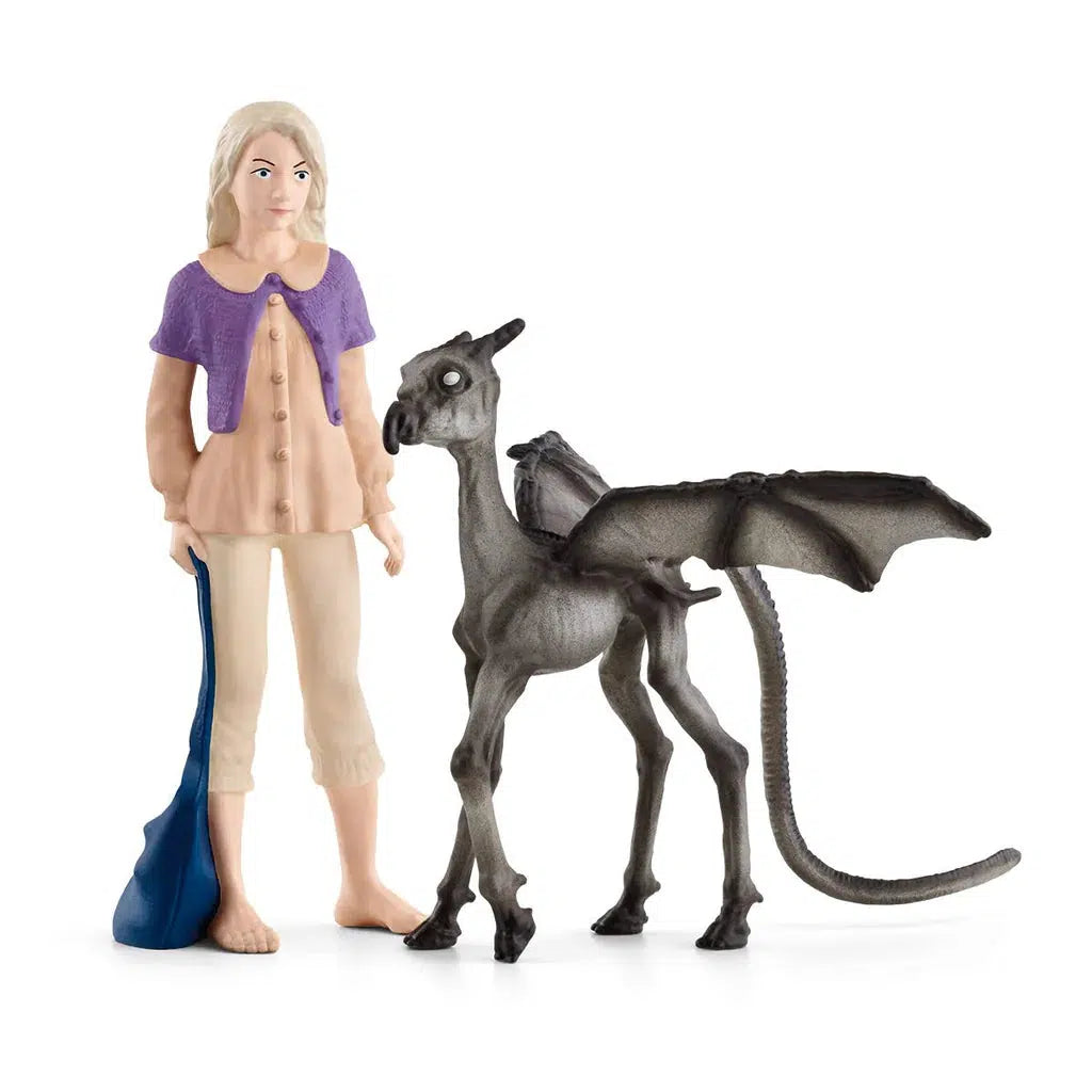 Luna Lovegood™, is seen here barefoot with her long blonde hair, her purple vest, and her blue bag. The little Thestral stands next to her with its wings spread out.