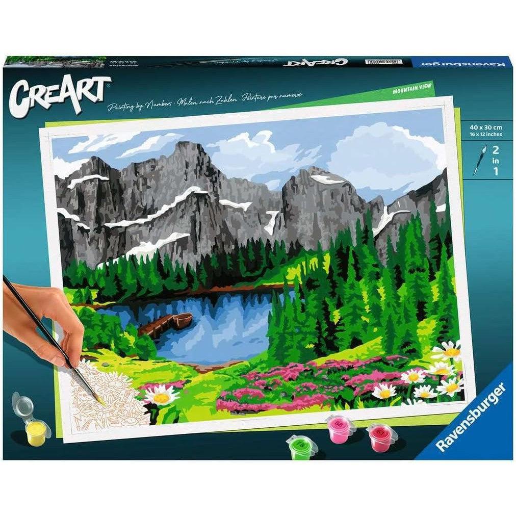 The Mountain View Paint-by-numbers kit showcases a picturesque mountain landscape with pine trees, a serene lake, and vibrant wildflowers in the foreground. Part of the Ravensburger CreArt collection, it features the iconic branding in the corner.