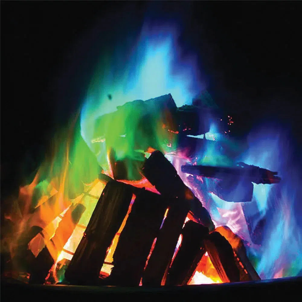 Display box of "Mystery Fire" packets, promising rainbow-colored flames for wood-burning fires. Box holds multiple black packets with vibrant, colorful branding.