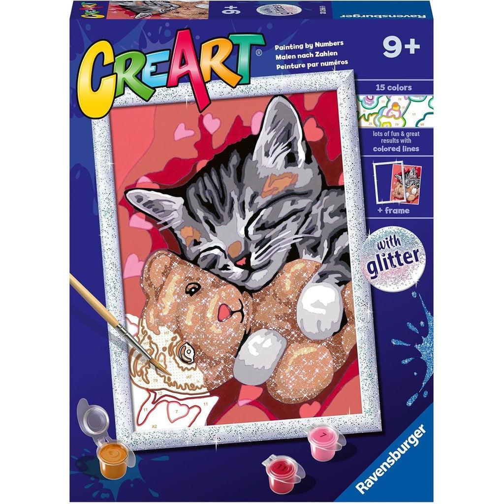 The CreArt painting kit box by Ravensburger features a delightful paint-by-numbers image of a gray tabby kitten cuddling a teddy bear. With 15 colors, glitter, and a frame included, this Kids Arts and Crafts set is perfect for ages 9 and up.