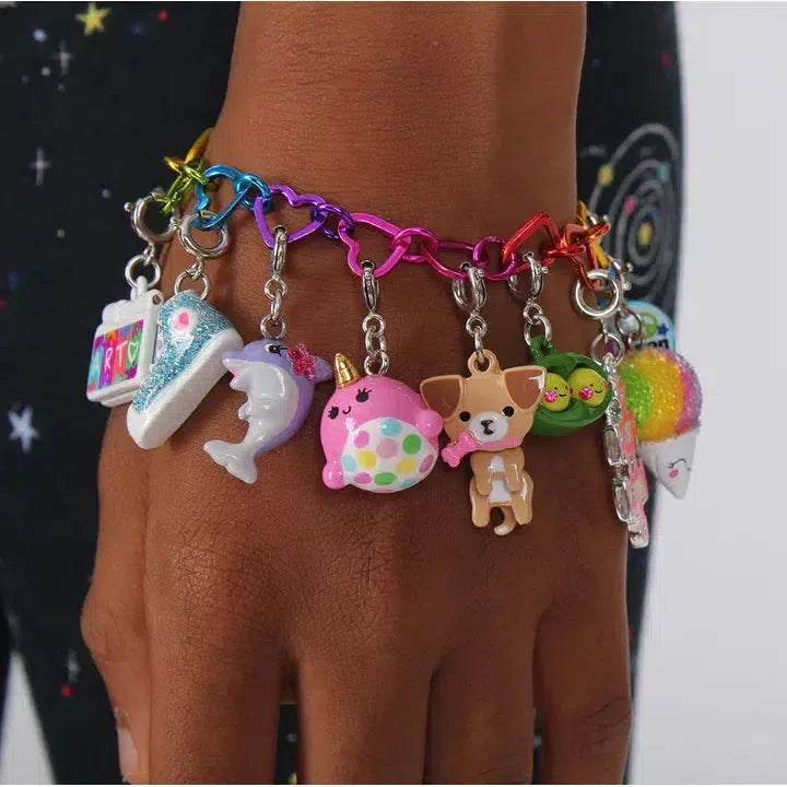 A colorful CHARM IT! bracelet featuring delightful characters like a taco, dog, dolphin, and even a unicorn graces a person's wrist against a dark patterned background.