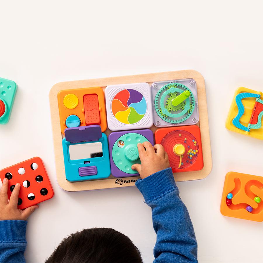 PlayTab modular sensory board with a child's hand as viewed from above while playing with one of the tabs.