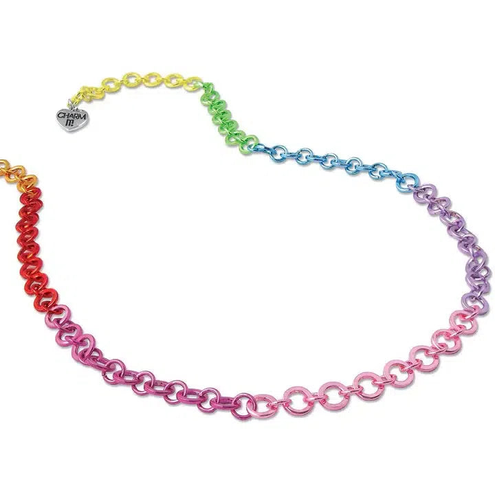 An adjustable rainbow-colored chain necklace featuring circular links and a small heart-shaped charm engraved with "CHARM IT!" near the clasp.