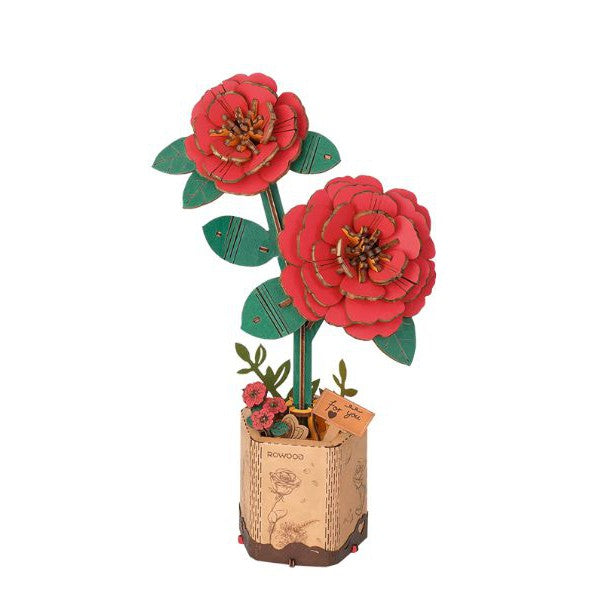 Two wooden red camellia flowers on one stem standing in a wooden base