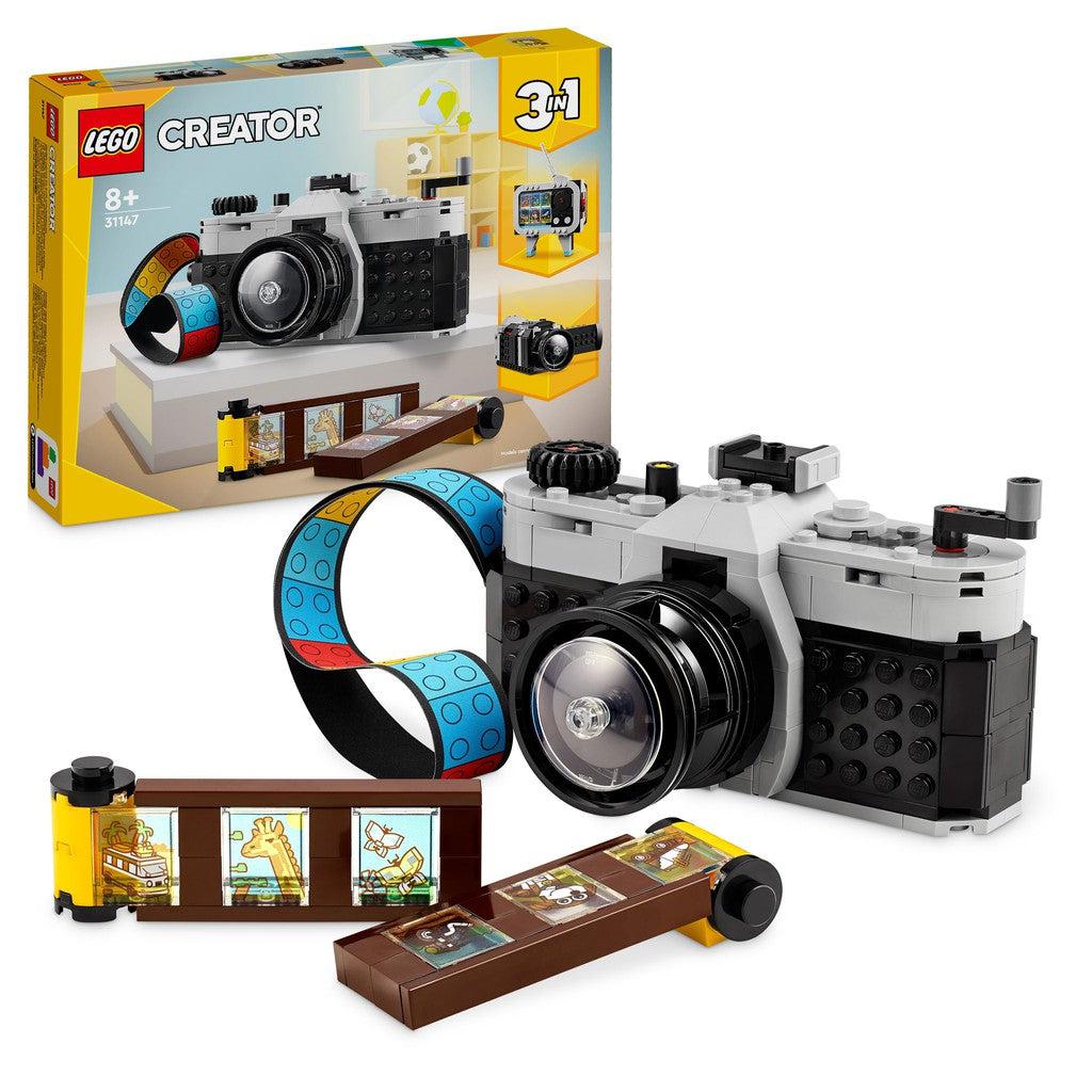 The lego set built as a camera is sitting in front of it's box.