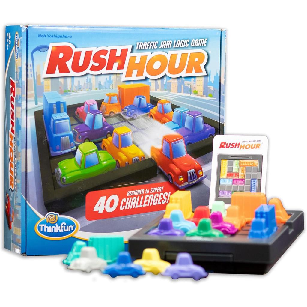 Box and game pieces of "Rush Hour," a STEM toy and traffic jam logic game. Includes 40 challenge cards and colorful vehicle pieces on a black grid.