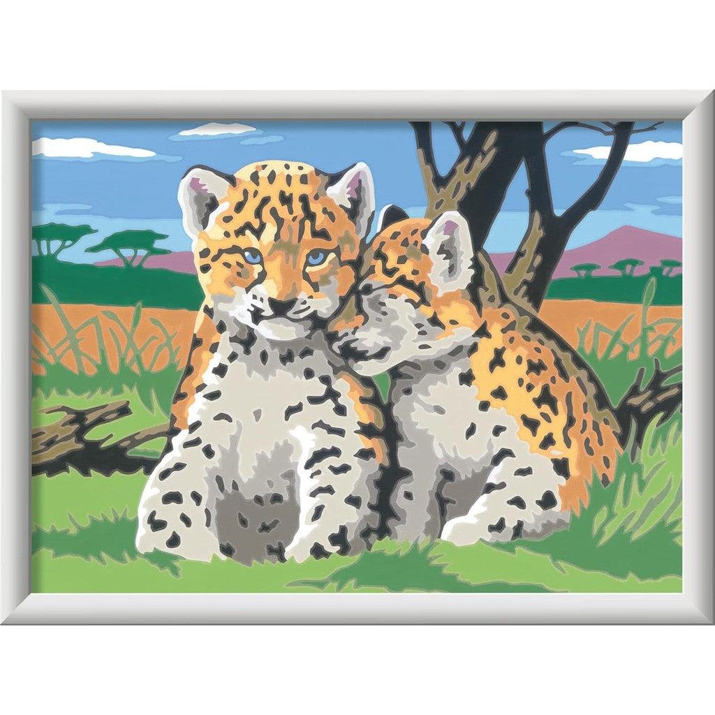 Two cartoon cheetahs sit together in a grassy savanna with trees and hills in the background, reminiscent of a charming Ravensburger Safari Friends scene. Perfect for arts and crafts enthusiasts, this can easily be transformed into an engaging paint-by-numbers experience.