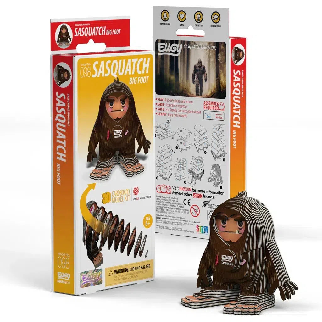 Cardboard model kit of a Sasquatch figure, resembling an eco-friendly 3D puzzle, with two packaging boxes in the background. It includes assembly instructions and a warning label, making it a perfect collectable toy for enthusiasts.