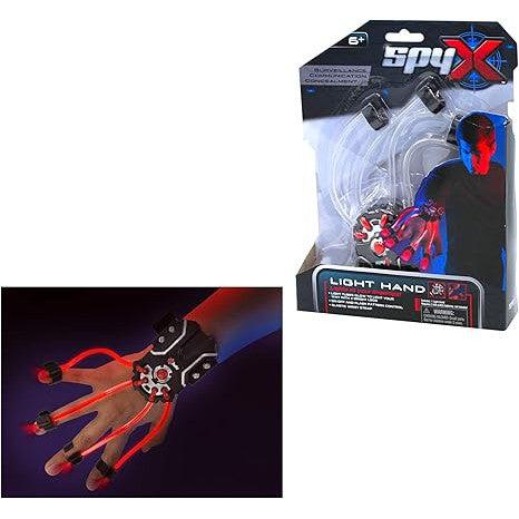 Toy packaging showcases the "Spy X Light Hand," an LED light-up glove with illuminated red lines on fingers, perfect for completing Secret Agent costumes. Designed for ages 6 and up, a child wearing the glove is shown against a dark background, capturing the essence of Spy Kids adventures.