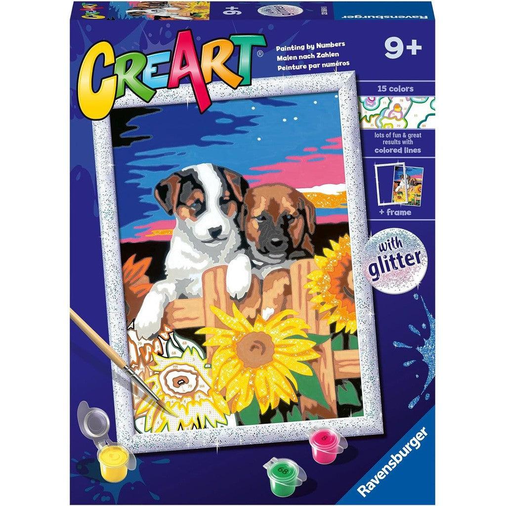 Discover the Ravensburger Paint by Numbers kit for ages 9 and up, featuring two adorable puppies in a vibrant landscape filled with sunflowers. This delightful arts and crafts set includes 15 colors, shimmering glitter, and a charming frame to complete your masterpiece.