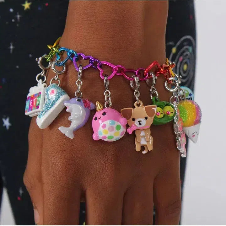 A colorful charm bracelet graces a person's wrist, perfect for any animal lover. It features a sneaker, dolphin, polka-dotted sphere, frog, rainbow snow cone, and a special dog charm.