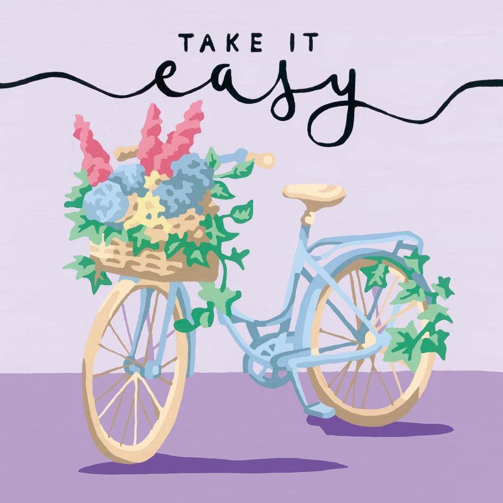 Illustration of a pale blue bicycle with a basket of colorful flowers on the front, reminiscent of a quaint Paint by Numbers kit. Text at the top reads "Take it easy.