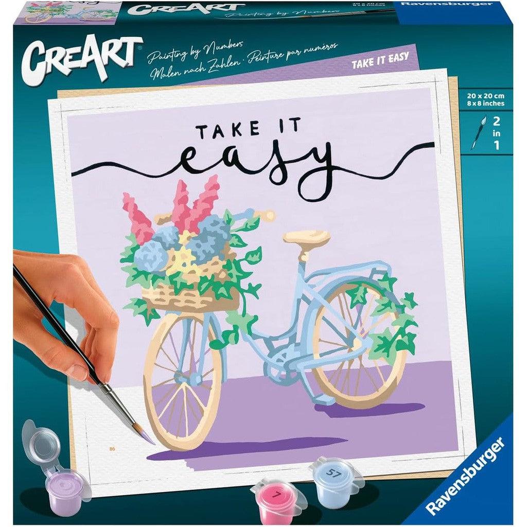 A Ravensburger paint-by-numbers kit package features a charming bicycle with a flower basket, complemented by the text "Take It Easy" above. Perfect for painting arts and crafts enthusiasts looking to unwind.