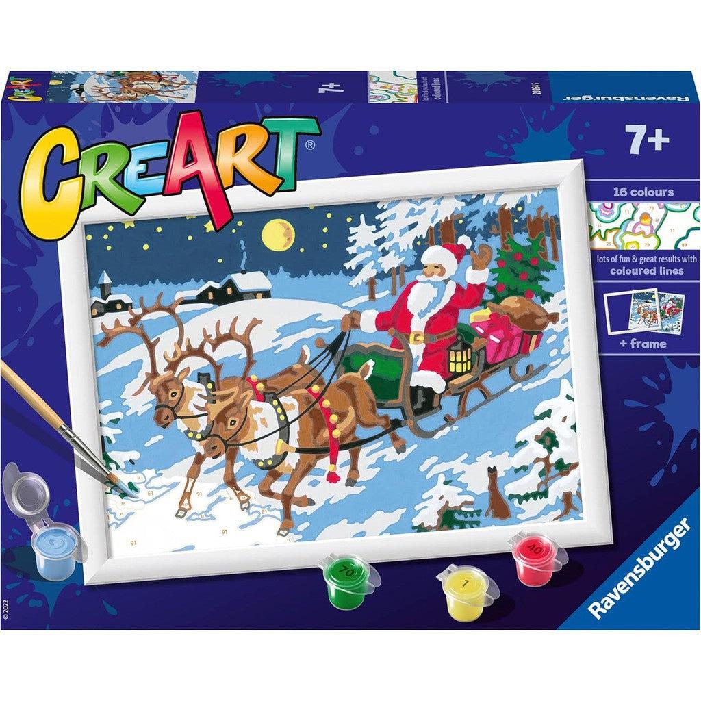 The Ravensburger CreArt Night Before Christmas paint-by-numbers kit features Santa Claus in a sleigh with reindeer over a snowy landscape and small village. It includes 16 vibrant colors, a brush, and a frame, perfect for ages 7 and up to enjoy during the festive season.