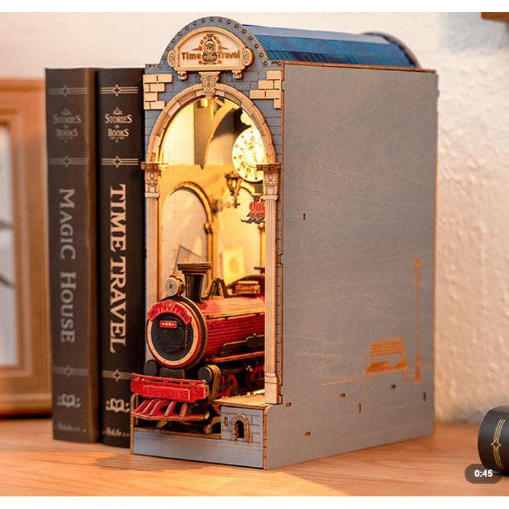 Book nook displayed on a shelf. The nook resembles a train station with a train popping out of the front