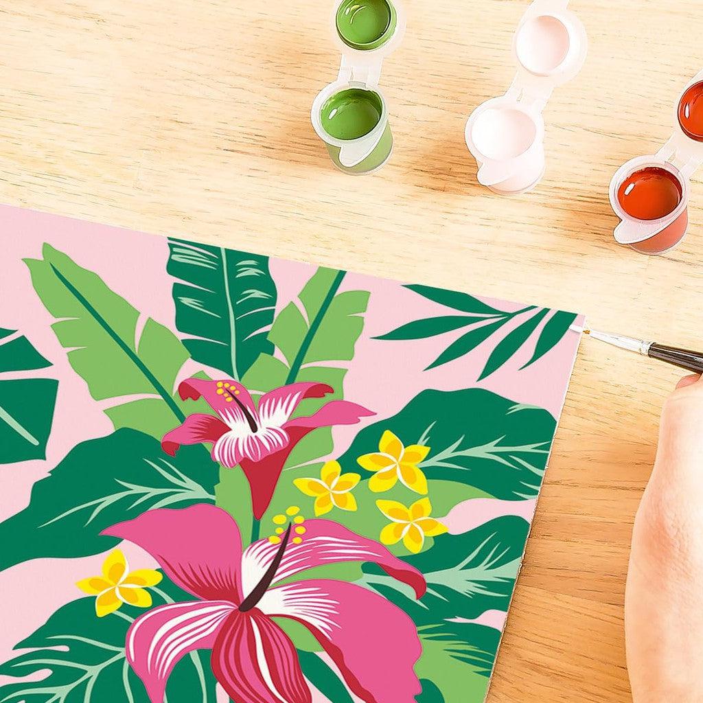 A vibrant painting of tropical leaves and flowers is meticulously crafted with paintbrushes, surrounded by open green and orange paint containers. This artwork embodies the essence of Painting Arts and Crafts, reminiscent of the precision found in Tropical Plants Paint by Numbers kits.