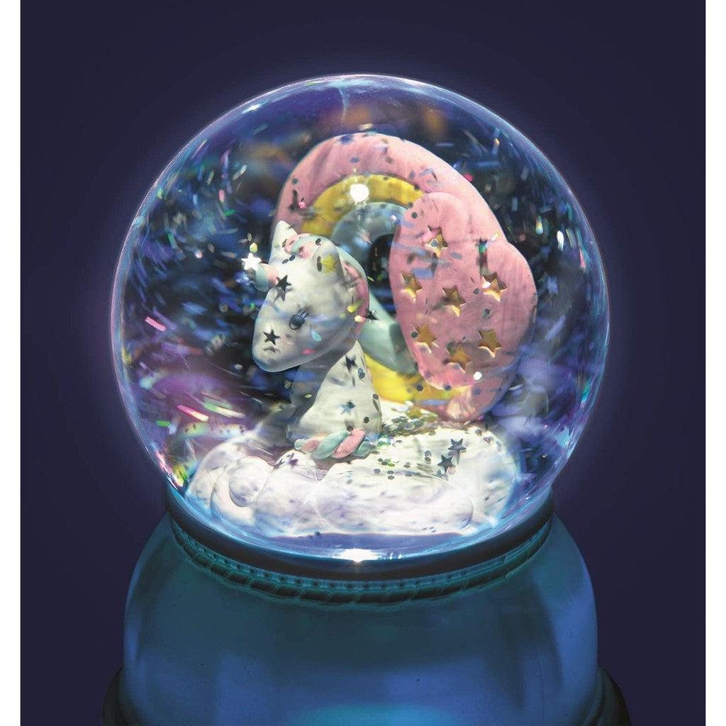 this unicorn snowglobe is also a nightlight. there is a unicorn with a rainbow mane surrounded by stars in the snowglobe.