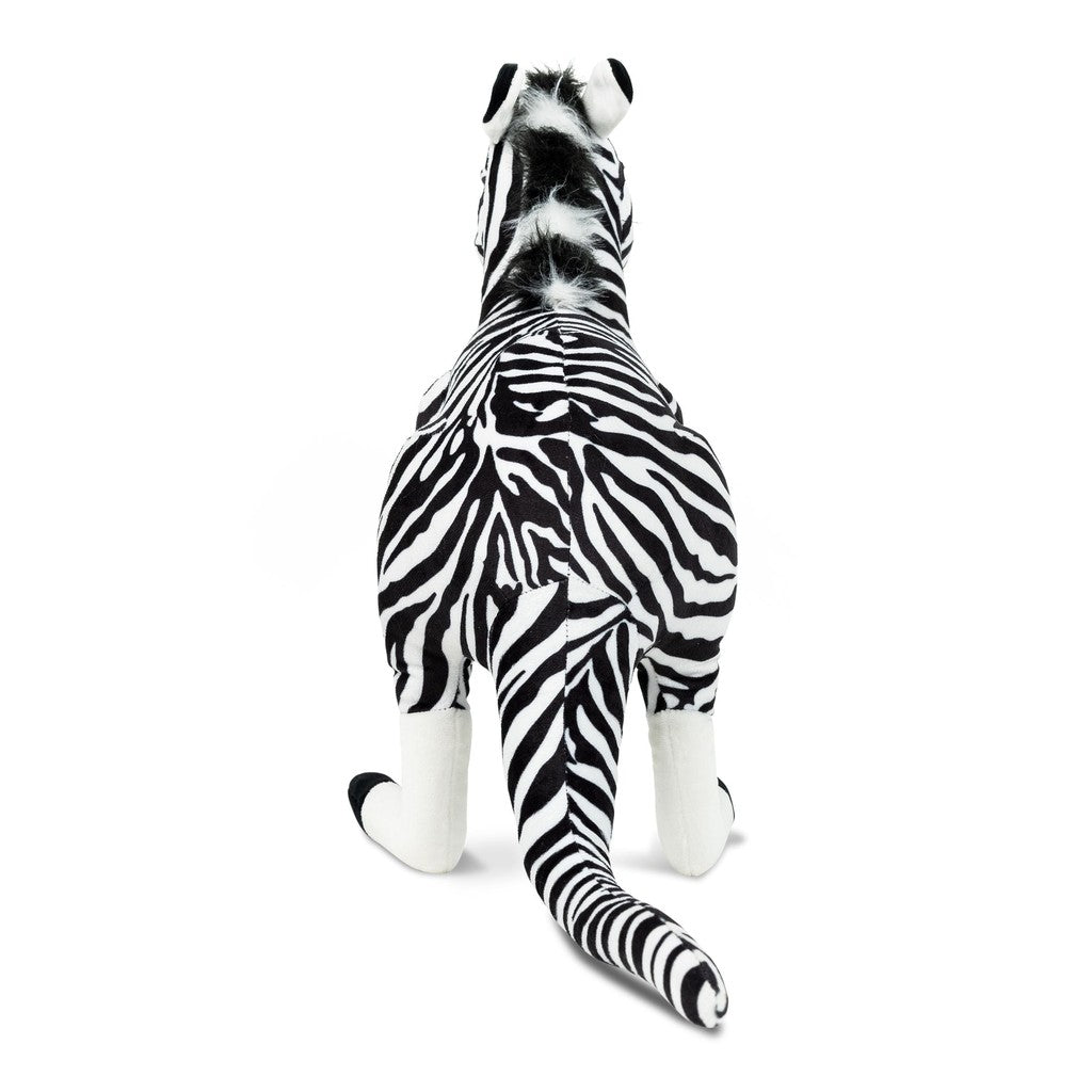 A plush zebra toy viewed from behind, sitting against a black background with a bright white glow surrounding it.