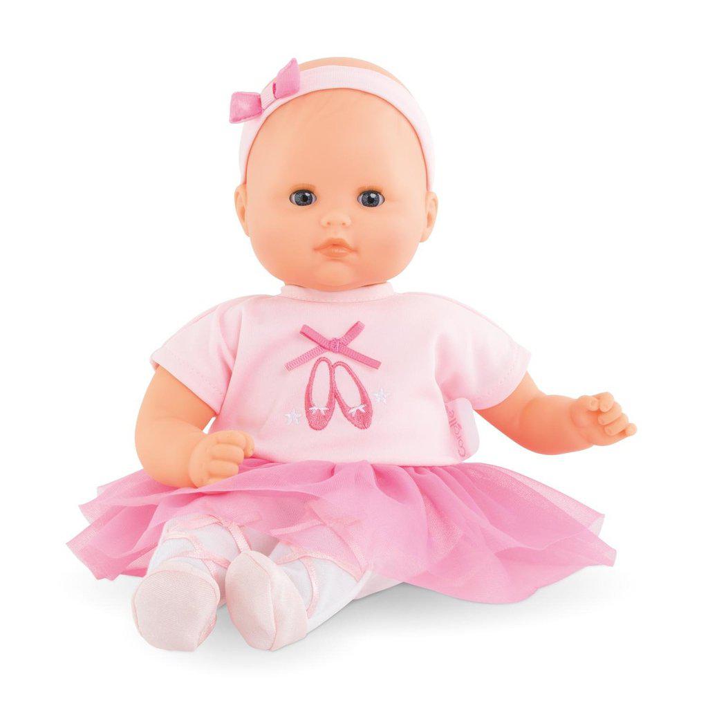 A baby doll wearing a pink ballerina outfit with a headband and pink tutu is seated, facing forward.